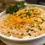 ['Close-up of creamy high-protein dip in a bowl, showcasing a rich texture.', 'Side view of a vibrant dip surrounded by fresh vegetables, highlighting its creamy consistency.', 'Appetizing pool dip featuring layers of shredded cheese and colorful ingredients.', 'Detailed image of a creamy dip with visible chunks of cheese and spices.']