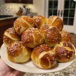 ['A close-up side view of golden-brown German soft pretzel bites on a wooden table.', 'Juicy German soft pretzel bites arranged neatly, showcasing their texture and color.', 'Side view of deliciously baked German soft pretzel bites, lightly salted and warm.', 'A detailed close-up of freshly baked German pretzel bites, highlighting their soft exterior.']