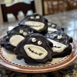 ['Close-up view of Ghost Cookies with white chocolate chips and black cocoa.', 'Side view of a plate of spooky Ghost Cookies decorated with black writing gel.', 'Juicy Ghost Cookies featuring a dark chocolate base and white chocolate pieces.', 'Deliciously crafted Ghost Cookies with ghostly decorations and a rich texture.']