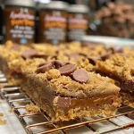 ['Juicy, golden-brown gluten-free peanut butter cookie bars with chocolate chips.', 'Close-up side view of decadent gluten-free peanut butter cookie bars topped with Reeses pieces.', 'A tempting slice of peanut butter cookie bar, showcasing a rich, creamy texture and chocolate chips.', 'Delicious gluten-free peanut butter cookie bars displayed on a rustic wooden board.']