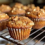 ['Close-up of a moist apple spice muffin with a golden-brown top and visible apple pieces.', 'Side view of a healthy muffin showcasing its spiced texture and garnished surface.', 'Juicy apple spice muffin highlighting the fluffy interior and crunchy walnut topping.', 'Freshly baked apple spice muffin with a warm, inviting appearance and apple chunks evident.']