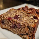 ['A close-up side view of a sliced Healthy Cranberry Pecan Banana Bread, showcasing its moist texture and vibrant cranberries.', 'A detailed side view of a loaf of Healthy Cranberry Pecan Banana Bread, highlighting the cranberries and pecans embedded in the bread.', 'An appetizing side view of healthy banana bread featuring cranberries and pecans, with a soft, golden-brown crust.', 'A close-up shot of Healthy Cranberry Pecan Banana Bread, revealing the rich colors of cranberries and the texture of the bread.']