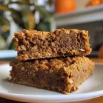 ['Close-up side view of Healthy Pumpkin Oatmeal Bars with a textured surface.', 'Juicy Healthy Pumpkin Oatmeal Bars displayed in a well-lit setting, showcasing ingredients.', 'Side view of freshly baked Healthy Pumpkin Oatmeal Bars with a golden hue and visible oats.', 'Delicious Healthy Pumpkin Oatmeal Bars cut into squares, highlighting their moist texture.']