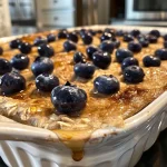 ['Close-up of a high-protein breakfast bake with blueberries.', 'Side view of a baked dish filled with oats, eggs, and cottage cheese.', 'Juicy breakfast bake topped with fresh blueberries and golden edges.', 'High-protein breakfast bake with a moist texture and vibrant blueberry topping.']