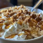 ['Close-up view of a creamy caramel apple cheesecake dip in a bowl, with a sprig of apple nearby.', 'A decadent high-protein caramel apple cheesecake dip topped with crushed Heath bar and served in a decorative dish.', 'Side view of a rich, caramel apple cheesecake dip with a smooth texture, garnished with apple slices.', 'A colorful bowl of caramel apple cheesecake dip featuring a glossy finish and layered ingredients.']