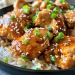['Close-up view of honey garlic chicken thighs garnished with scallions and sesame seeds.', 'Juicy slow cooker chicken thighs glazed with a honey garlic sauce.', 'Side view of tender chicken thighs served with rice and topped with sesame seeds.', 'Appetizing honey garlic chicken thighs presented in a bowl with green onions.']