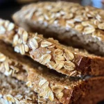['Close-up view of golden-brown Maple Oat Bread with a textured crust.', 'Side angle of freshly baked Maple Oat Bread showcasing its soft interior and crust.', 'Juicy Maple Oat Bread partially sliced, revealing its moist and fluffy texture.', 'Rustic Maple Oat Bread displayed on a wooden surface, emphasizing its hearty appearance.']