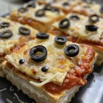 ['Close-up of Mummy Pizzas topped with olives and mozzarella, placed on a wooden surface.', 'Side view of delicious Mummy Pizzas, featuring spooky olive eyes, ready to be served.', 'Juicy Mummy Pizzas with melted cheese and black olives, captured with a smartphone.', 'A plate of Mummy Pizzas, showcasing their golden crust and intricate edible designs.']