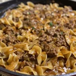 ['A close-up of a plate of One-Pan Beef and Noodles showcasing juicy ground beef and egg noodles.', 'Side view of a serving of One-Pan Beef and Noodles highlighting the creamy sauce and garnished with herbs.', 'A delicious bowl of One-Pan Beef and Noodles featuring tender beef, noodles, and a rich broth.', 'A vibrant dish of One-Pan Beef and Noodles with a mixture of beef, noodles, and spices glistening.']