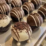 ['Close-up view of Oreo truffles coated in chocolate.', 'Side view of delicious chocolate-covered Oreo truffles.', 'Juicy Oreo truffles with chocolate coating and sprinkles.', 'Sweet dessert truffles made with Oreos and cream cheese.']
