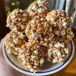['Close-up view of a shiny, golden popcorn ball with a textured surface.', 'Side view of delicious popcorn balls arranged on a white plate, showing their fluffy texture.', 'Juicy popcorn balls glistening with syrup, captured in vibrant detail.', 'A cluster of popcorn balls featuring a mix of golden and slightly caramelized colors.']