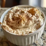 ['A close-up side view of a creamy, protein-packed churro cheesecake dip in a bowl, topped with a sprinkle of cinnamon.', 'A delicious serving of Protein Churro Cheesecake Dip with a smooth texture, garnished with cinnamon and a hint of sweetness.', 'A textured side view of Protein Churro Cheesecake Dip, showcasing its creamy consistency and enticing ingredients.', 'A mouth-watering bowl of Protein Churro Cheesecake Dip, highlighted by a side perspective revealing its richness and toppings.']