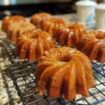 ['Close-up side view of moist Pumpkin Mini Bundt Cakes with a golden-brown exterior.', 'Side view of delicious Pumpkin Mini Bundt Cakes decorated with cream cheese icing and sprinkled with pumpkin pie spice.', 'Juicy Pumpkin Mini Bundt Cakes displayed on a white plate, highlighting their intricate bundt shape.', 'An iPhone 15 Pro photo capturing the texture and details of freshly baked Pumpkin Mini Bundt Cakes.']