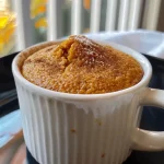 ['A close-up side view of a pumpkin mug cake topped with a sprinkle of pumpkin spice.', 'A juicy pumpkin mug cake in a white mug, showcasing its moist texture.', 'Detailed side view of a pumpkin mug cake with a vibrant orange color and creamy surface.', 'An iPhone 15 Pro captured image of a pumpkin mug cake, highlighting its fluffy consistency.']