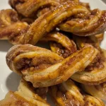 ['Close-up view of Pumpkin Pie Spice Cinnamon Twists on a plate.', 'Side view of golden-brown cinnamon twists drizzled with frosting.', 'Juicy Pumpkin Pie Spice Cinnamon Twists displayed beautifully.', 'Deliciously twisted bread dough with pumpkin spice flavor.']