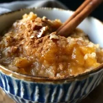 ['A close-up side view of creamy Pumpkin Spice Rice Pudding topped with golden raisins and pecans.', 'A detailed shot of Pumpkin Spice Rice Pudding served in a bowl, showcasing its vibrant orange hue.', 'A side view of a bowl filled with Pumpkin Spice Rice Pudding garnished with nuts and spices.', 'An image of delicious Pumpkin Spice Rice Pudding, highlighting its rich texture and festive toppings.']