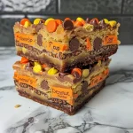 ["Close-up of Reese's Cake Mix Cookie Bars with colorful Reese's Pieces on top.", "Side view of delicious cookie bars featuring chunks of Reese's Peanut Butter Cups.", 'Juicy, gooey dessert bars made from yellow cake mix and topped with chocolate candies.', "Close-up shot highlighting the rich texture and toppings of Reese's cookie bars."]