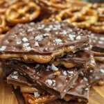 ['Close-up view of Salted Caramel Pretzel Bark featuring a mix of chocolate and pretzels.', 'Side view of a slice of Salted Caramel Pretzel Bark displaying its crunchy texture and caramel drizzle.', 'Detailed shot of Salted Caramel Pretzel Bark showing the chocolate layer and pretzel pieces.', 'Close-up image of Salted Caramel Pretzel Bark highlighting the rich chocolate and caramel blend.']