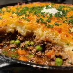 ["Juicy Skillet Shepherd's Pie with golden potato topping in a cast-iron skillet.", "Close-up view of Shepherd's Pie, showcasing its hearty layers and crispy top.", 'Savory dish featuring ground beef and vegetables topped with creamy mashed potatoes.', "Delicious homemade Shepherd's Pie, baked to perfection in a skillet."]