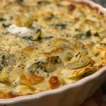 ['Close-up of a creamy spinach artichoke dip served in a white bowl with a golden brown crust.', 'Detailed view of a delicious spinach artichoke dip, featuring bits of spinach and artichoke, ready for dipping.', 'Creamy spinach artichoke dip in a bowl, showcasing its rich texture and vibrant green color.', 'Side view of a savory spinach artichoke dip, garnished and surrounded by tortilla chips.']