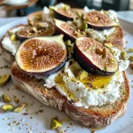 ['Close-up of whipped ricotta toast topped with roasted figs and honey, garnished with crushed pistachios.', 'Side view of a slice of whipped ricotta toast, featuring halved figs and a drizzle of honey.', 'A delicious serving of whipped ricotta toast with roasted figs, pistachios, and a sprinkle of flaky sea salt.', 'Artistic presentation of whipped ricotta toast, showcasing juicy figs, honey drizzles, and vibrant toppings.']